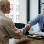 Dois profissionais em um ambiente de escritório apertando as mãos após um acordo de negócios, simbolizando a resolução de questões relacionadas a juros abusivos.